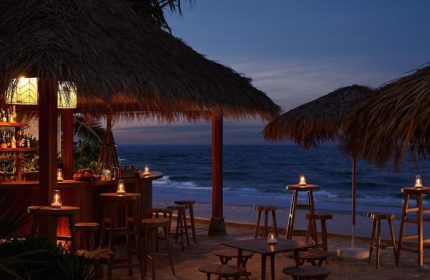 Romantic gay beach resort Hua Hin, The Standard. Beach bar with thatched roof, tables, and chairs at dusk. Perfect for gay travel.