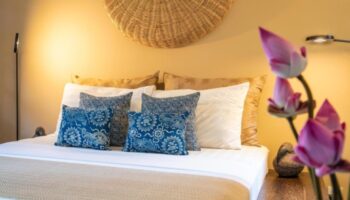 Rambutan Resort Siem Reap bedroom. Romantic gay hotel near gay bars. Bed with blue patterned pillows and lotus flowers. Gay travel in Cambodia.
