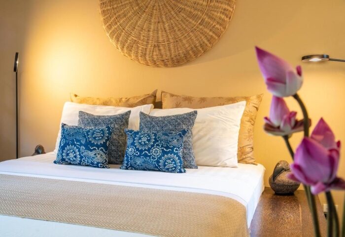 Rambutan Resort Siem Reap bedroom. Romantic gay hotel near gay bars. Bed with blue patterned pillows and lotus flowers. Gay travel in Cambodia.
