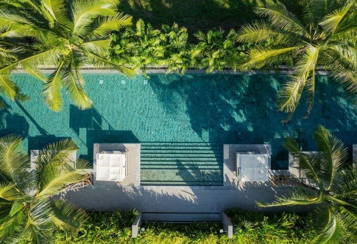 Aerial view of Melia Phuket Mai Khao, a romantic gay beach resort. Lush palm trees surround a tranquil pool, perfect for a honeymoon getaway.