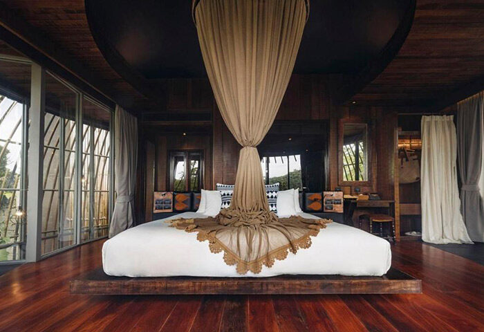Keemala Phuket honeymoon suite. Unique gay-friendly hotel idea for couples. Luxurious bedroom with canopy bed, wood floors, and nature views.