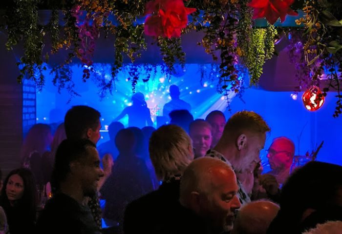 Moulin Rose Gay Club in Sitges: Crowd enjoys the show with blue lights and floral decor. Gay nightlife travel advice in Spain.