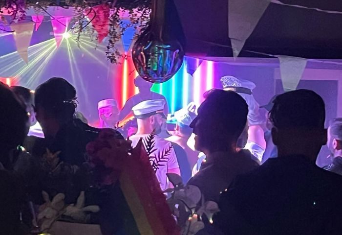 Inside Moulin Rose Gay Club in Sitges. Men enjoy the nightlife, with rainbow lights and decorations. Gay travel advice.