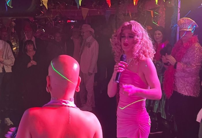 Moulin Rose Gay Club in Sitges: Drag queen performing at a gay bar with pink lights and partygoers. Gay travel in Sitges, Spain.