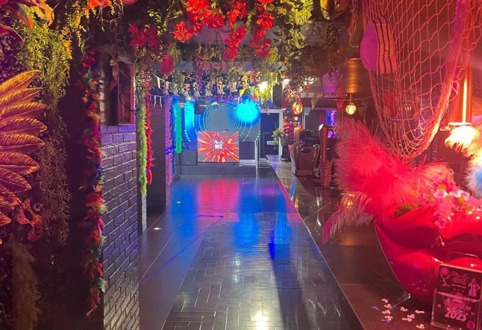 Interior of Moulin Rose, a gay club in Sitges. The club features colorful decorations, including flowers and a disco ball. Gay travel advice.