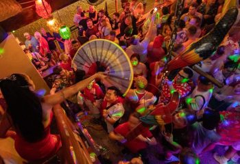 Crowded Mr. Flamingo gay bar in Puerto Vallarta. Drag queen performance, colorful lights, and lively atmosphere. Gay travel destination.