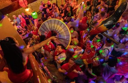Crowded Mr. Flamingo gay bar in Puerto Vallarta. Drag queen performance, colorful lights, and lively atmosphere. Gay travel destination.