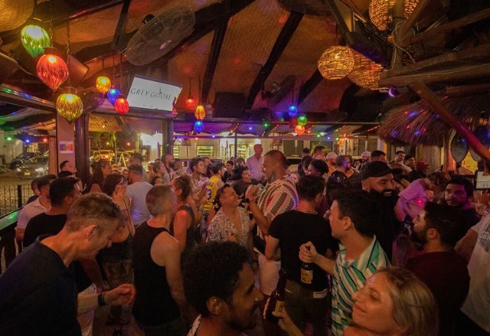 Crowded Mr. Flamingo Gay Bar in Puerto Vallarta, Mexico. People socializing under colorful lights and ceiling fans. Nightlife scene.