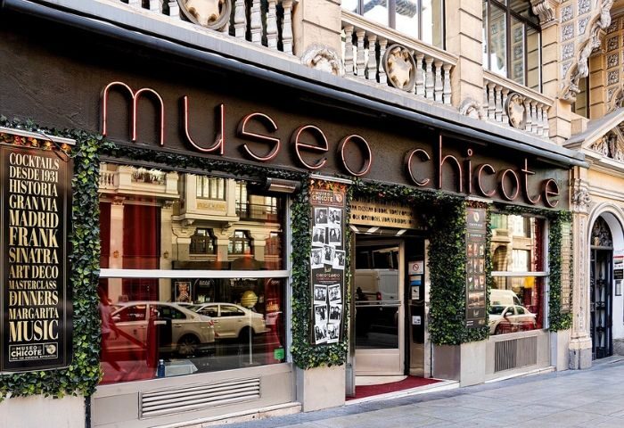 Facade of Museo Chicote, a gay-friendly bar in Madrid. Neon sign, ivy decor, and vintage posters. Popular Gran Via cocktail destination.