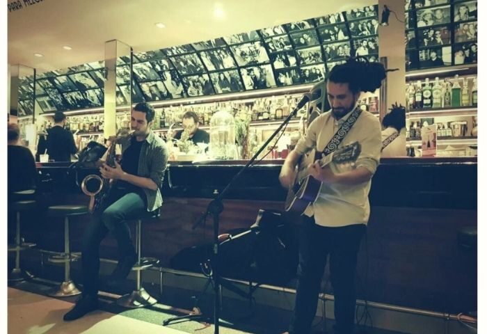 Live music at Museo Chicote, a gay bar in Madrid. Saxophone and guitar players perform in front of the bar. Gay travel.