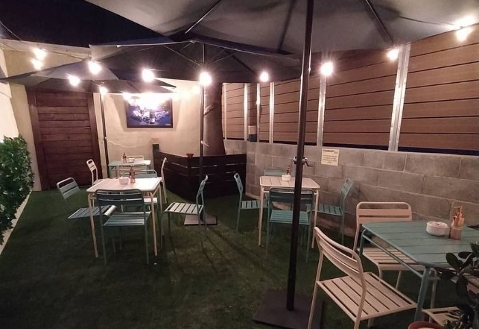 Barcelona gay bar patio with tables, chairs, and string lights. Outdoor seating area at a museum bar, perfect for gay men travel.