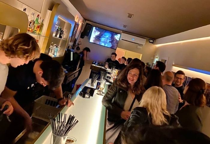 Barcelona gay bar scene: Museum Bar. Patrons at the bar, enjoying drinks, and socializing. A DJ is playing music. Nightlife.
