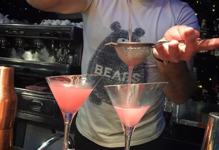 Bartender making pink cocktails at My Bar, Rome. Gay bar with Bears t-shirt. Gay travel advice, nightlife, and Rome's gay scene.