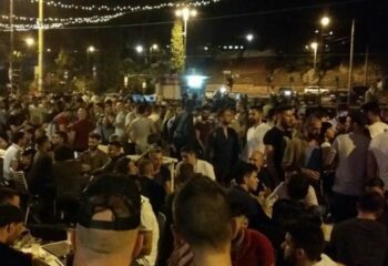 Night view of a crowded gay bar in Rome. Many men are standing and sitting at tables, enjoying the nightlife scene. Gay travel advice.
