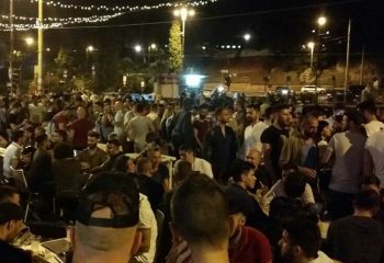 Night view of a crowded gay bar in Rome. Many men are standing and sitting at tables, enjoying the nightlife scene. Gay travel advice.