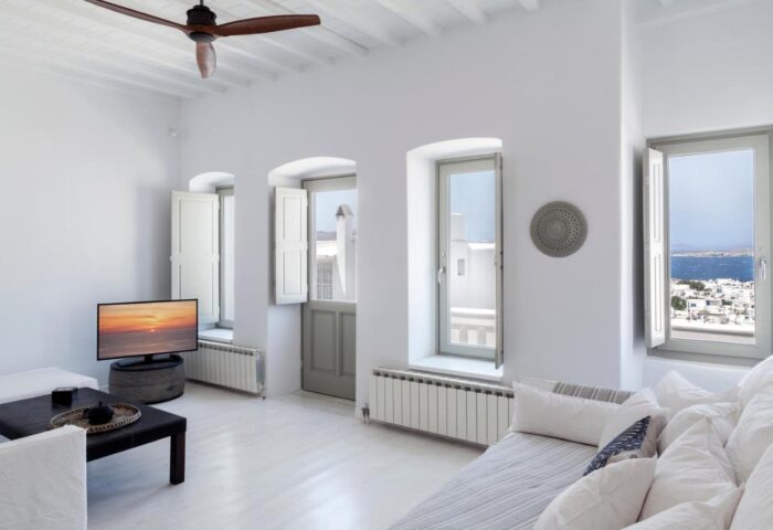 Myconian Inn gay budget hotel room. White interior with sea view, windows, and minimal decor. Ideal for gay travel in Mykonos.