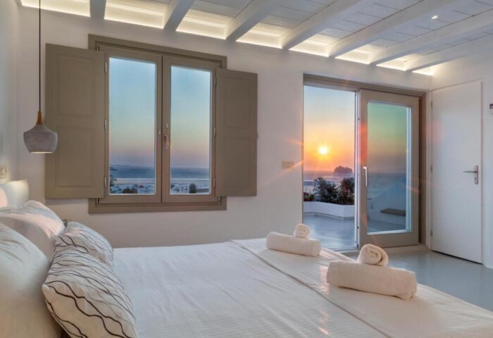 Myconian Inn gay budget hotel room. Sunset view from bed. Travel advice for gay men. Mykonos hotel room with sea view. Budget travel.