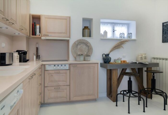 Myconian Inn gay budget hotel kitchenette. Interior of Mykonos hotel room with cabinets, stove, breakfast bar, stools, and coffee maker.