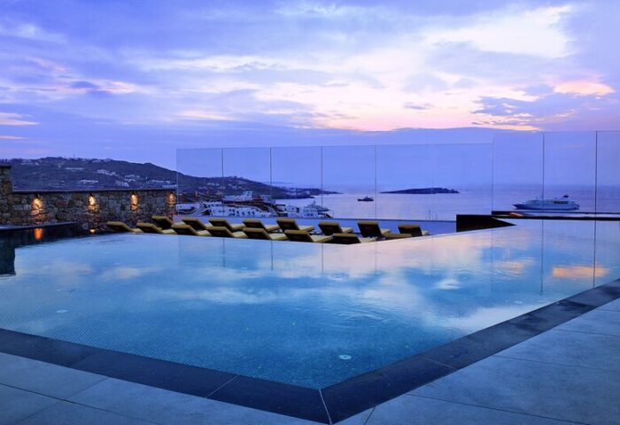 Myconian Korali, a gay hotel in Mykonos. Infinity pool view of the Aegean Sea at sunset. Luxury travel for gay men in Greece.