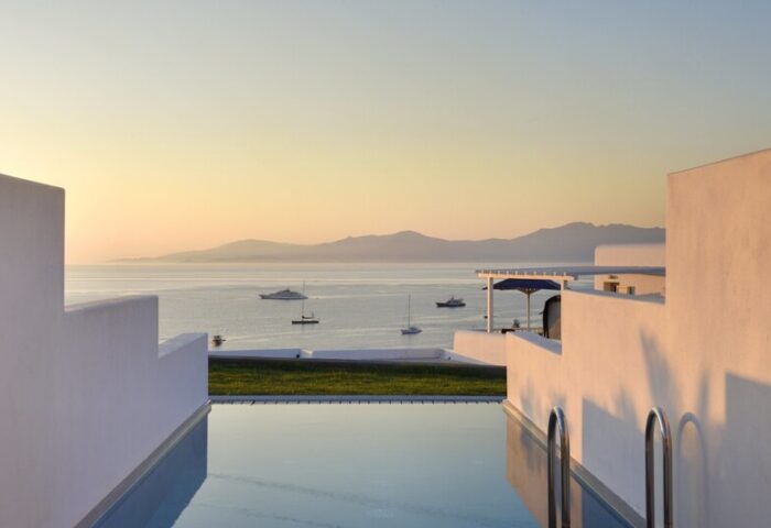 Myconian Korali, Mykonos gay hotel view. Yachts on the sea, seen from a luxury pool. Gay travel destination in Greece.