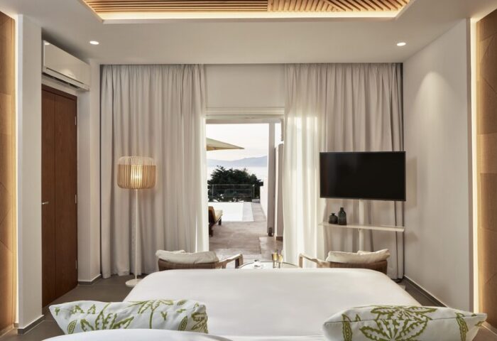 Myconian Korali gay hotel room in Mykonos, Greece. Luxurious interior with sea view, white linens, and modern design. Travel destination for gay men.