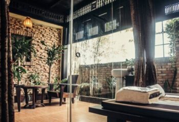 NaDam Spa Ho Chi Minh: Interior view of the spa with massage table, brick walls, plants, and natural light. Gay travel advice.