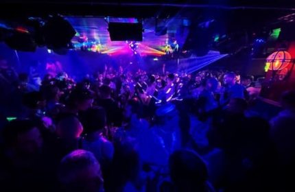 Never Mind Bar Copenhagen: A crowded gay bar with blue lighting and laser beams. Nightlife scene for gay men traveling in Copenhagen.