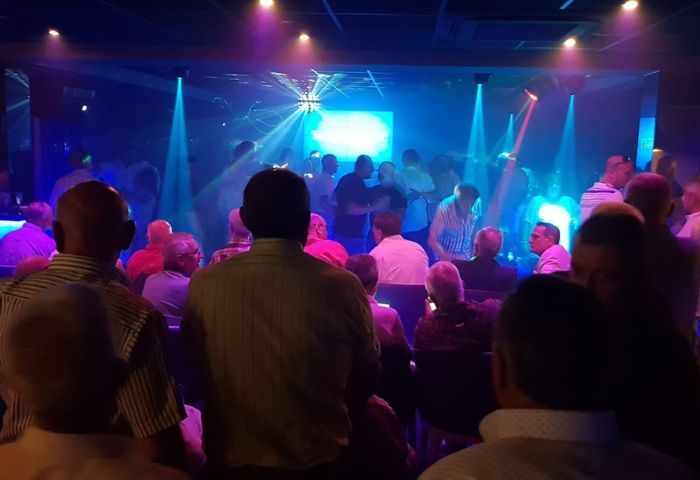 Interior view of Incognito Gay Bar in Benidorm, Spain. People gather under blue lights. Gay travel destination, nightlife scene.