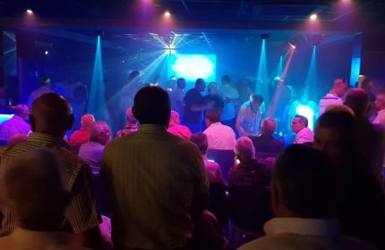 Interior view of Incognito Gay Bar in Benidorm, Spain. People gather under blue lights. Gay travel destination, nightlife scene.
