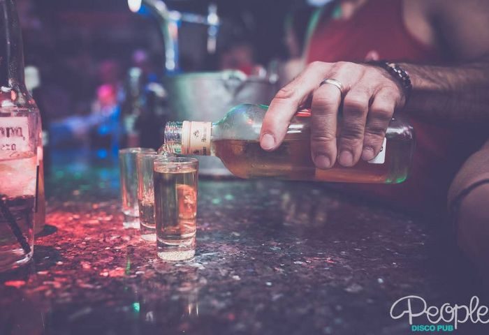 Drinks at New People Gay Bar in Benidorm. Bartender pouring shots at a popular gay bar. Nightlife and gay travel in Benidorm, Spain.