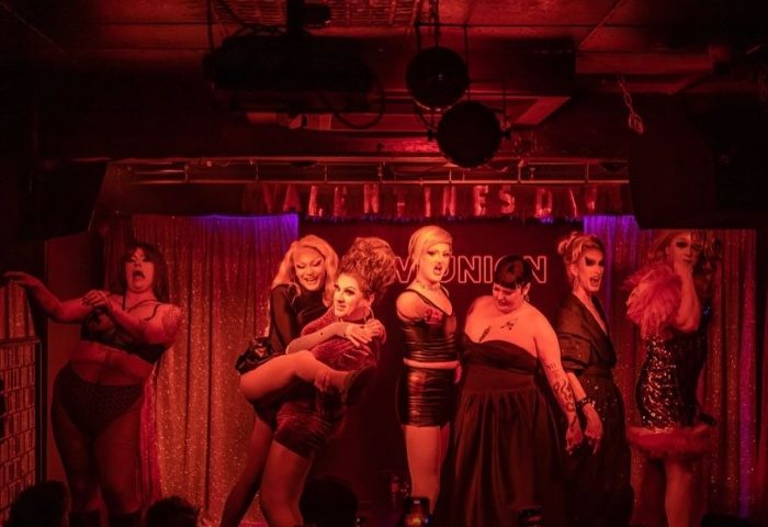 Drag queens perform at New Union Manchester, a gay bar. Valentine's Day sign in background. Nightlife for gay men.