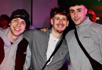 Three gay men smiling at New Union, Manchester. Gay travel advice. Nightlife scene, friends, happy, LGBTQ+, United Kingdom.