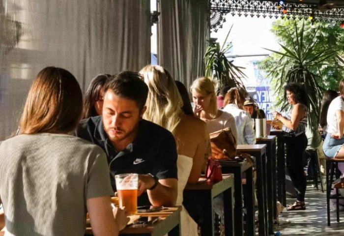 Patio scene at Newtown Hotel Sydney. People at tables, some with drinks. Gay travel advice for a good time in Sydney, Australia.