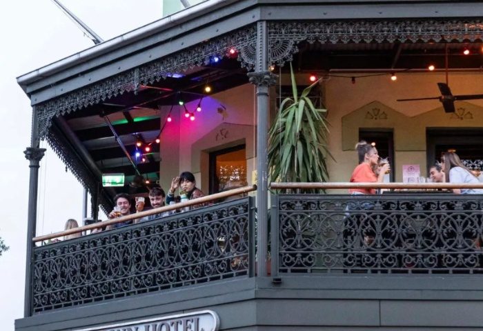 Newtown Hotel Sydney balcony view. People socializing, drinking, and enjoying the atmosphere at this gay-friendly travel destination.