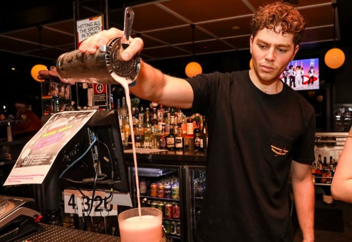 Bartender pours a pink cocktail at Newtown Hotel, Sydney. Gay travel advice: enjoy the vibrant nightlife and friendly atmosphere.