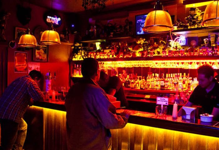 Gay party at Nicho Bears Bar in Mexico. Interior view of men at the bar with bottles and warm lighting. Gay travel advice.