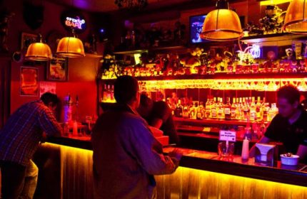 Gay party at Nicho Bears Bar in Mexico. Interior view of men at the bar with bottles and warm lighting. Gay travel advice.