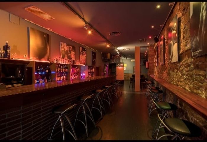 Night Barcelona Gay Cruise Club Interior. Bar with stools, bottles, and artwork. A popular gay bar in Barcelona for gay men travel.
