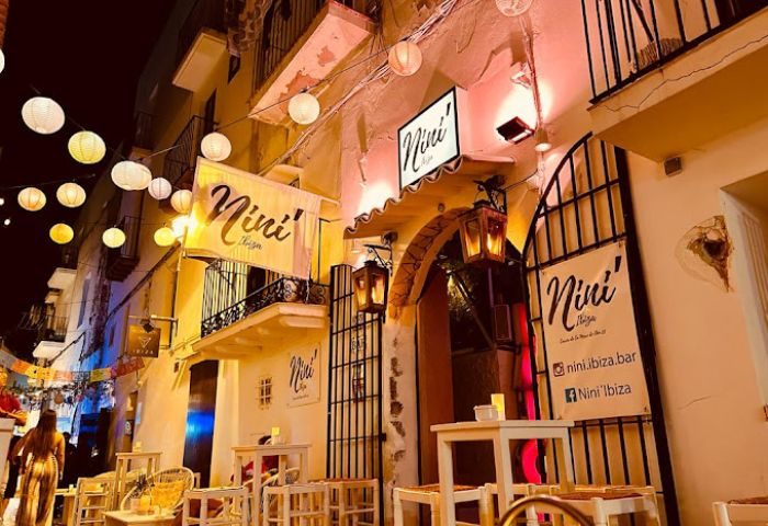 Nini' Ibiza bar at night. Gay bar and party venue in Ibiza, Spain. Outdoor seating, lanterns, and a lively atmosphere. Gay travel destination.