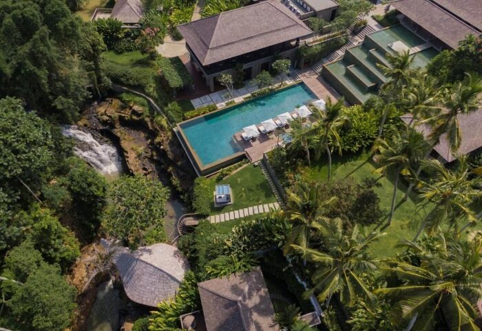 Aerial view of Nirjhara Bali, a gay-friendly hotel. Private pool villa with waterfall backdrop. Best for gay travel in Bali. Lush tropical setting.