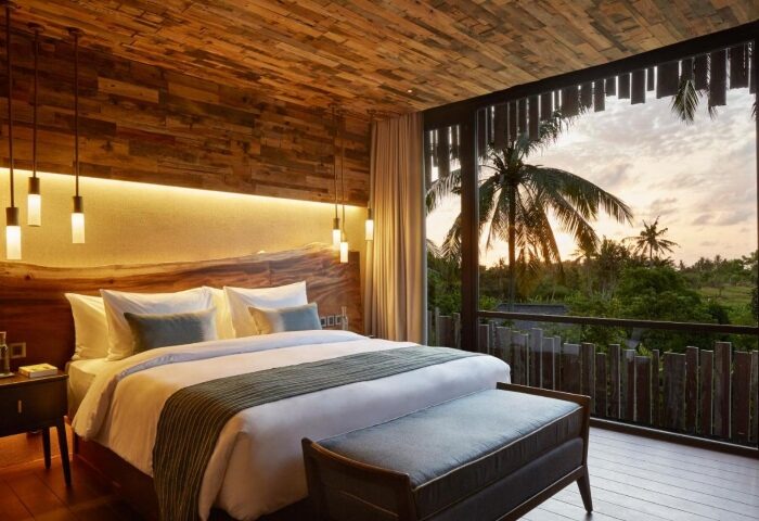 Gay honeymoon hotel Bali: Nirjhara's perfect room. Wood accents, king bed, & balcony with jungle view. Ideal for romantic gay travel.