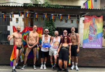 Gay group at NoLoSo Bar, Milan. Rainbow flags, shirtless men, and vibrant energy capture the gay travel scene in Milan, Italy.