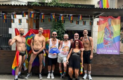 Gay group at NoLoSo Bar, Milan. Rainbow flags, shirtless men, and vibrant energy capture the gay travel scene in Milan, Italy.