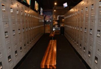 Locker room at North Hollywood Spa. Lockers line the walls with wooden benches in the center aisle. A gay spa experience in North Hollywood.