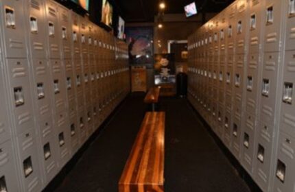 Locker room at North Hollywood Spa. Lockers line the walls with wooden benches in the center aisle. A gay spa experience in North Hollywood.