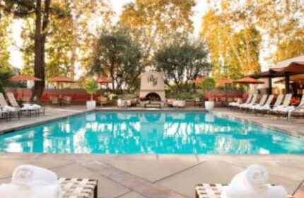 North Hollywood Spa pool. Outdoor pool at gay-friendly spa with lounge chairs, umbrellas, fireplace, and trees. Relaxing travel destination.