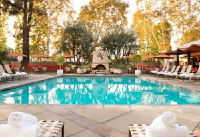 North Hollywood Spa pool. Outdoor pool at gay-friendly spa with lounge chairs, umbrellas, fireplace, and trees. Relaxing travel destination.