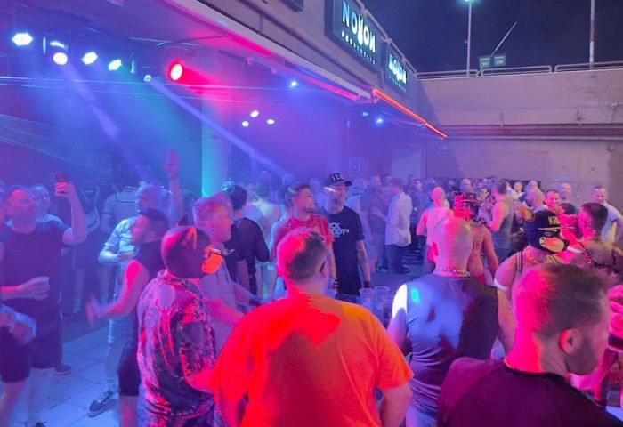 Noxon Terrace Gay Bar in Gran Canaria. Crowded scene with men dancing under colorful lights. Gay nightlife travel advice.
