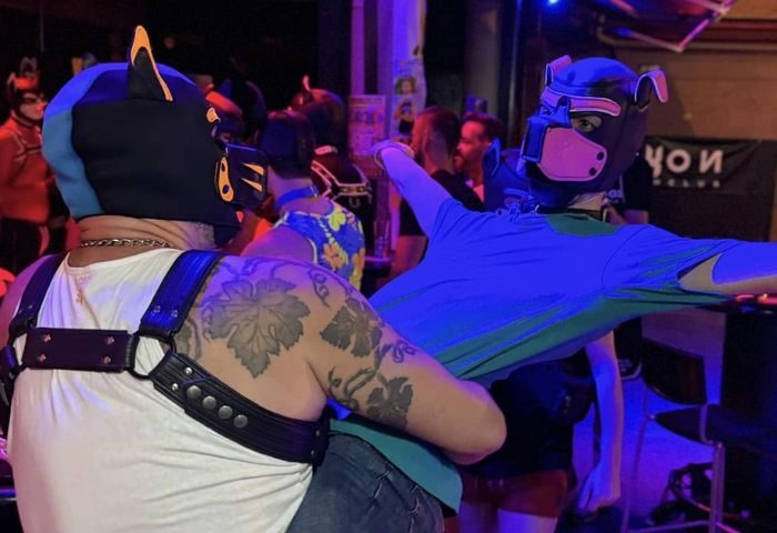 Gay Gran Canaria: Men in pup masks at Noxon Terrace gay bar. Leather harnesses, tattoos, and vibrant nightlife scene. Gay travel advice.