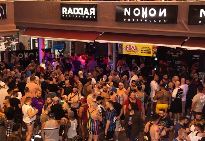 Crowded Noxon Terrace gay bar in Gran Canaria. Gay nightlife scene, men socializing at a popular gay venue. Maspalomas gay travel destination.